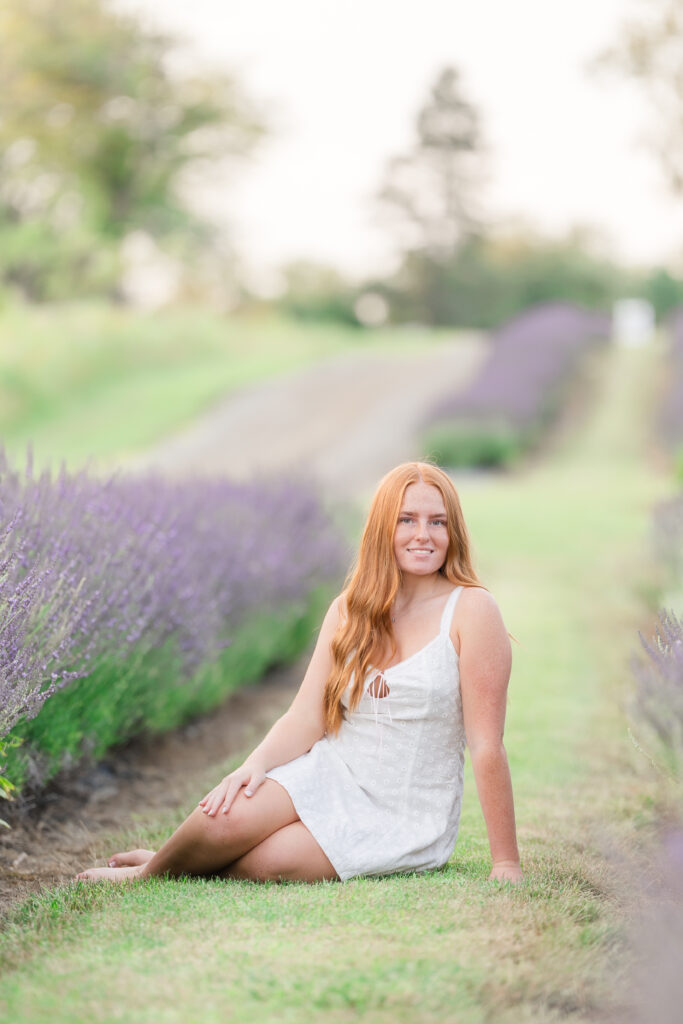 Senior girl in a white dress standing in a lavender field in Mid Michigan during golden hour.