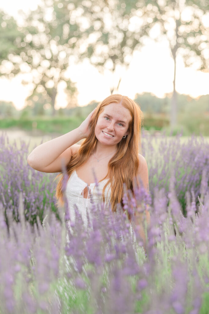 Senior girl in a white dress standing in a lavender field in Mid Michigan during golden hour.