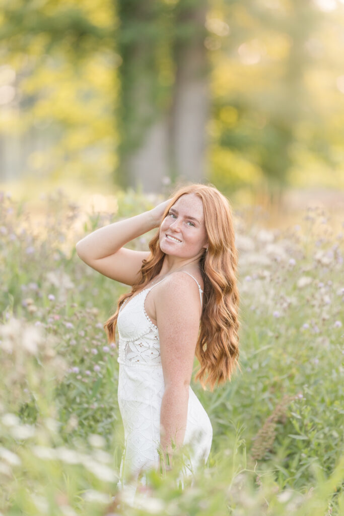 Senior girl in a white dress standing in a lavender field in Mid Michigan during golden hour.