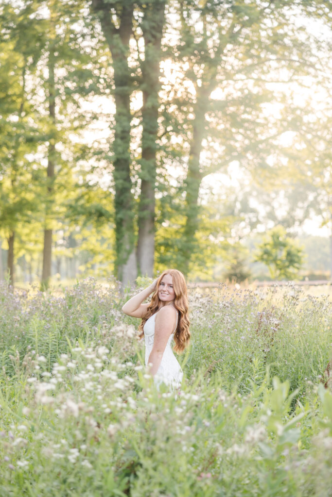Senior girl in a white dress standing in a lavender field in Mid Michigan during golden hour.