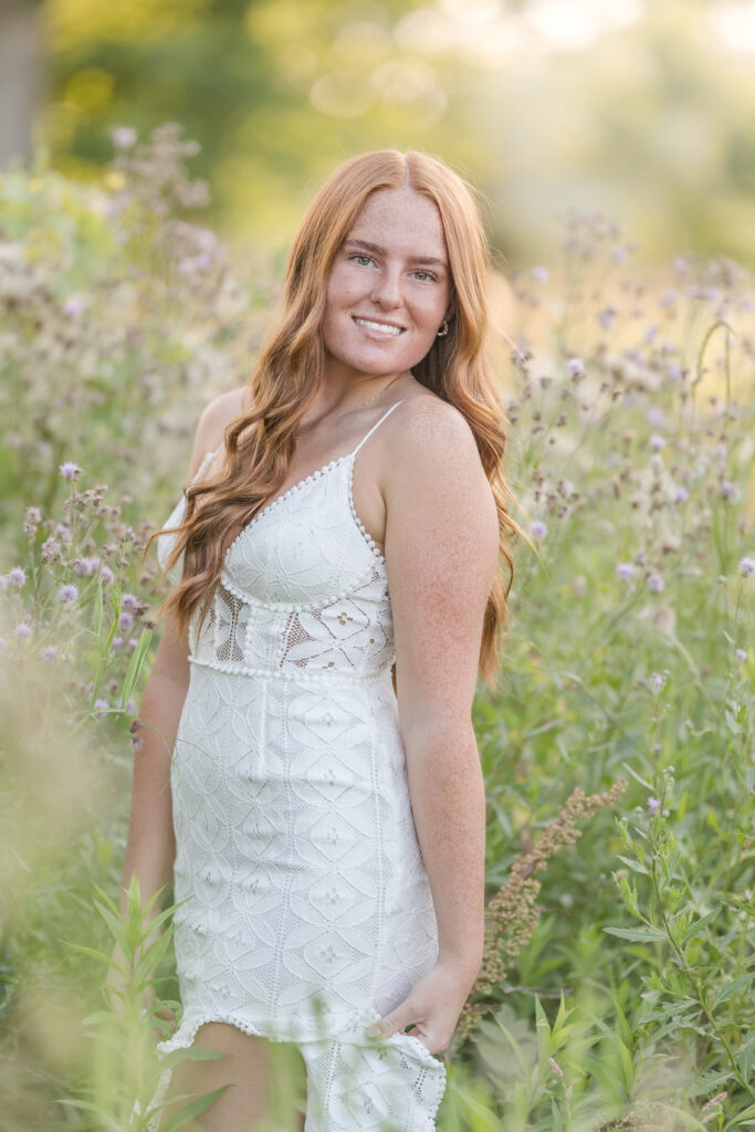 Senior girl in a white dress standing in a lavender field in Mid Michigan during golden hour.