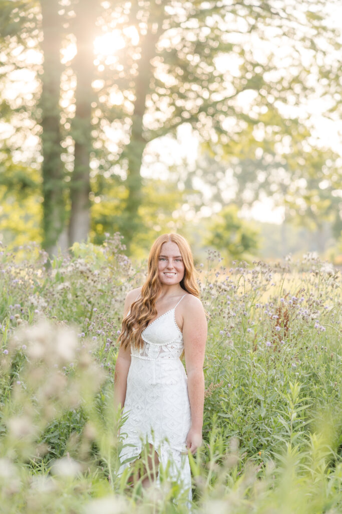 Senior girl in a white dress standing in a lavender field in Mid Michigan during golden hour.