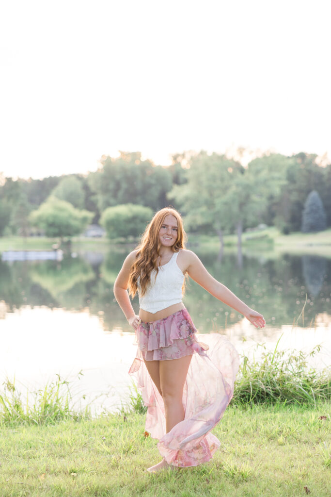 Senior girl in a white dress standing in a lavender field in Mid Michigan during golden hour.