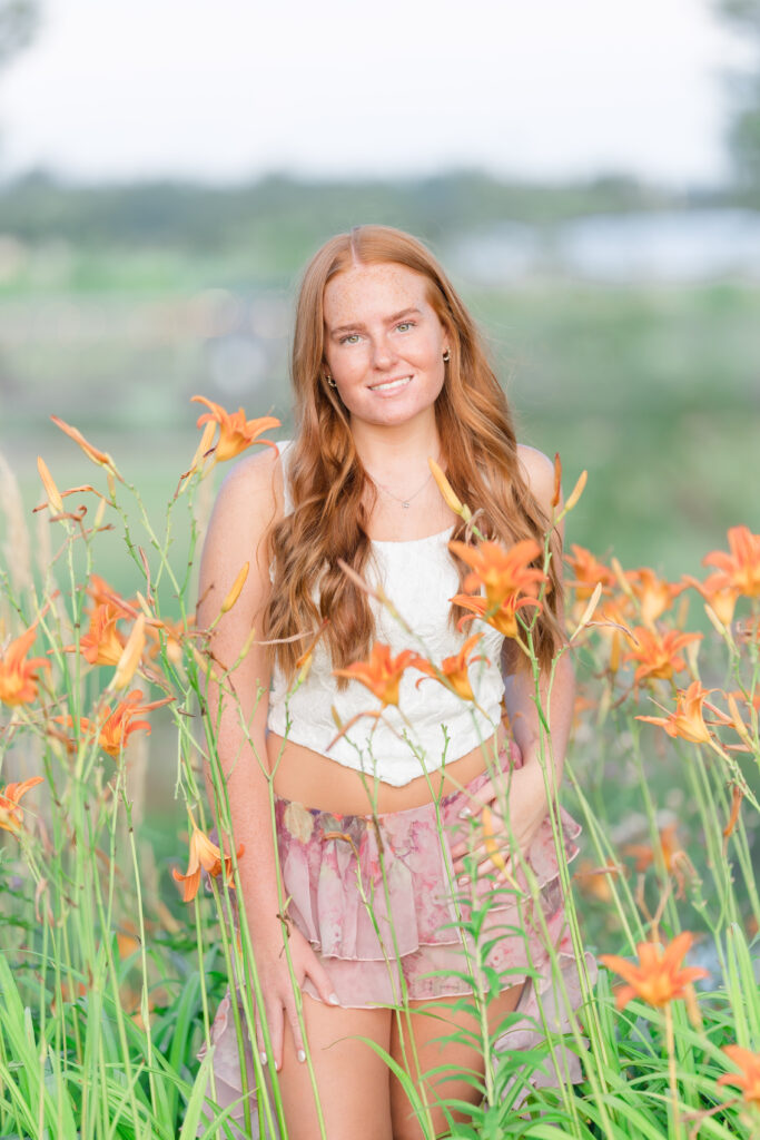 Senior girl in a white dress standing in a lavender field in Mid Michigan during golden hour.